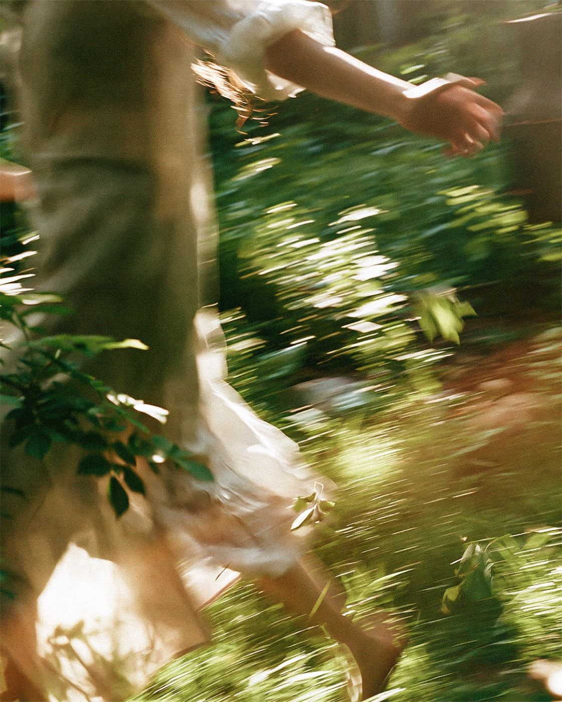 A woman in a white dress running beneath a great tree in morning light